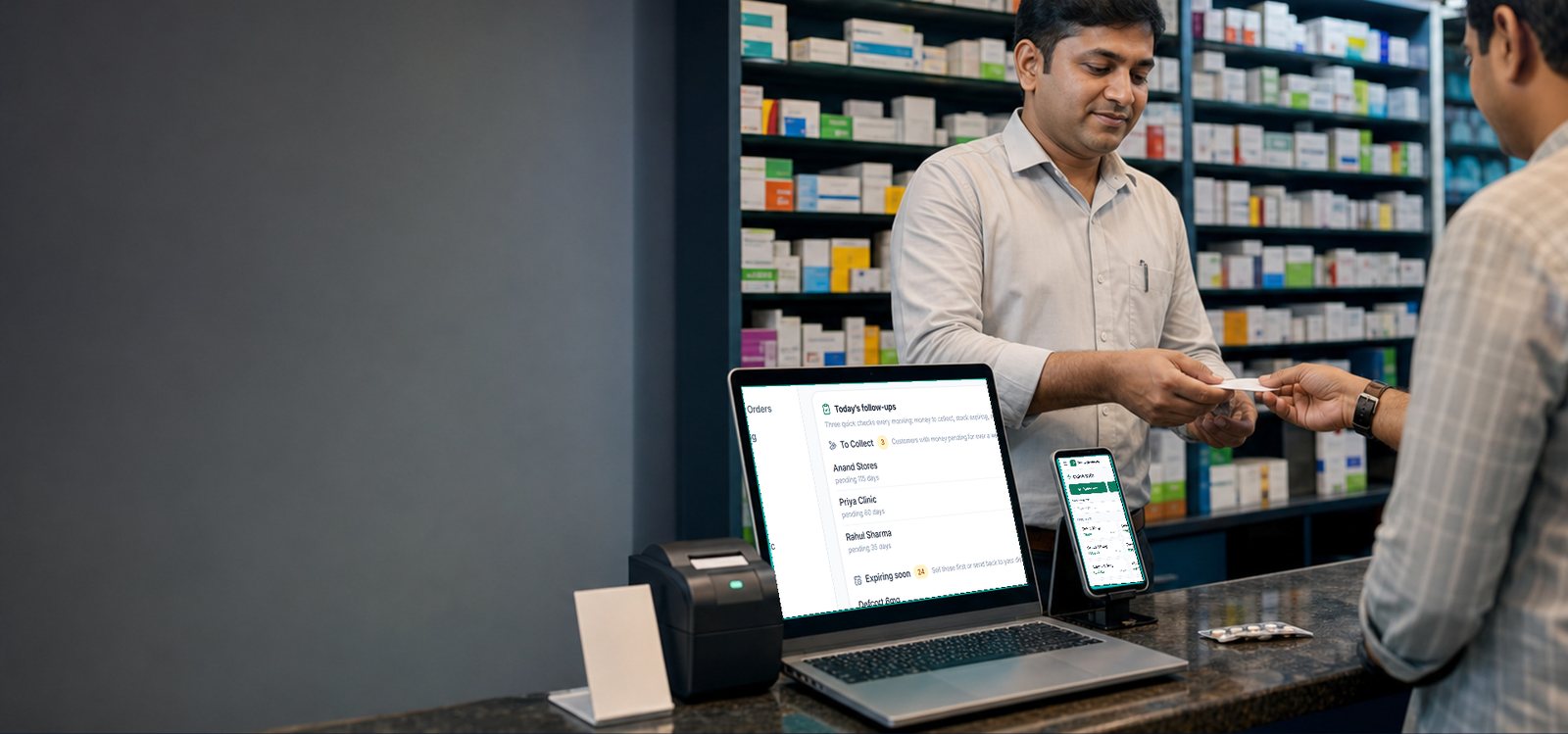 A chemist at his counter handing over a bill, with Entyti open on a laptop showing the day's follow ups and on a phone showing the Quick Sale screen.